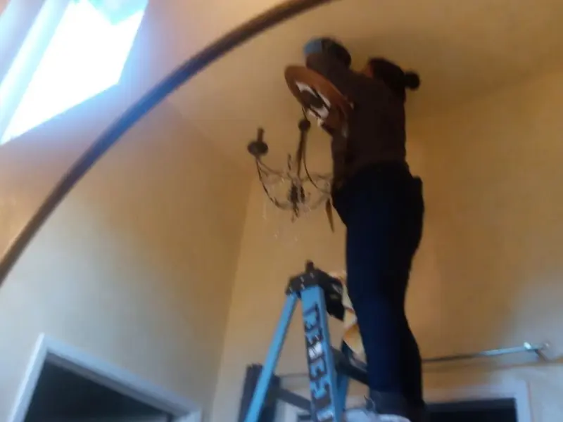 Electrician installing a chandelier in a Deep River residence